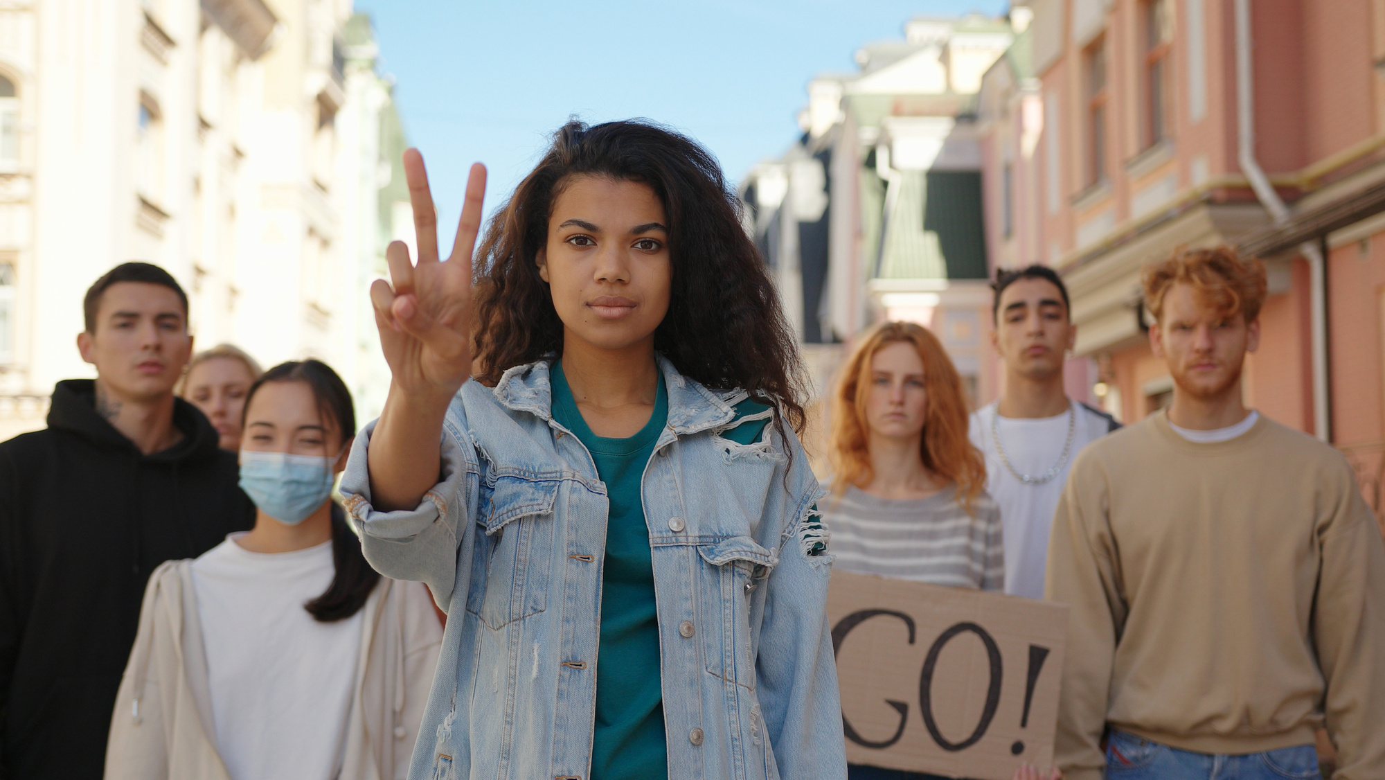 Mixed race woman leader at multiethnic protest shows peace gesture. Peaceful protesting demonstration